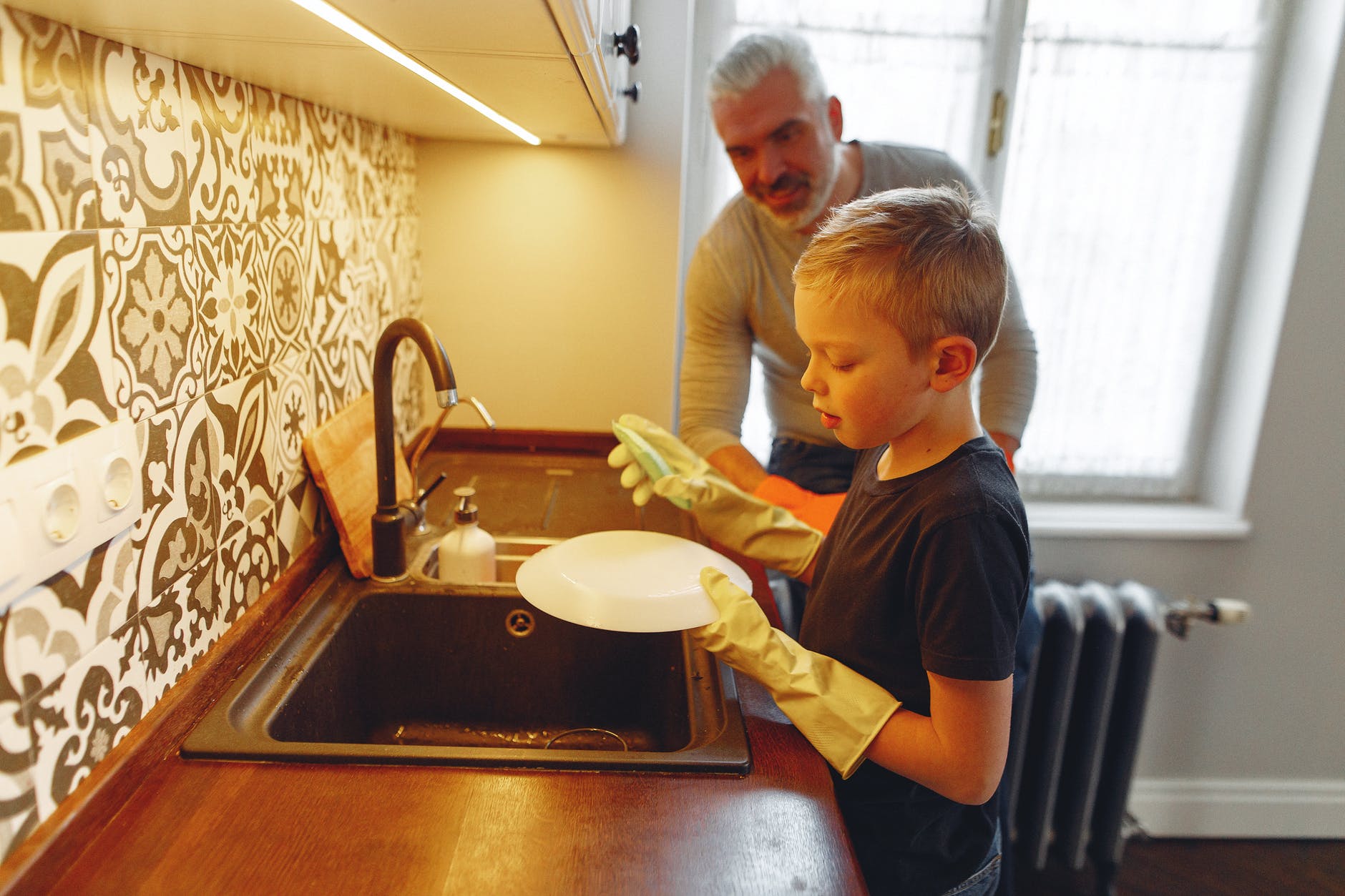 father teaching son dishwashing at kitchen